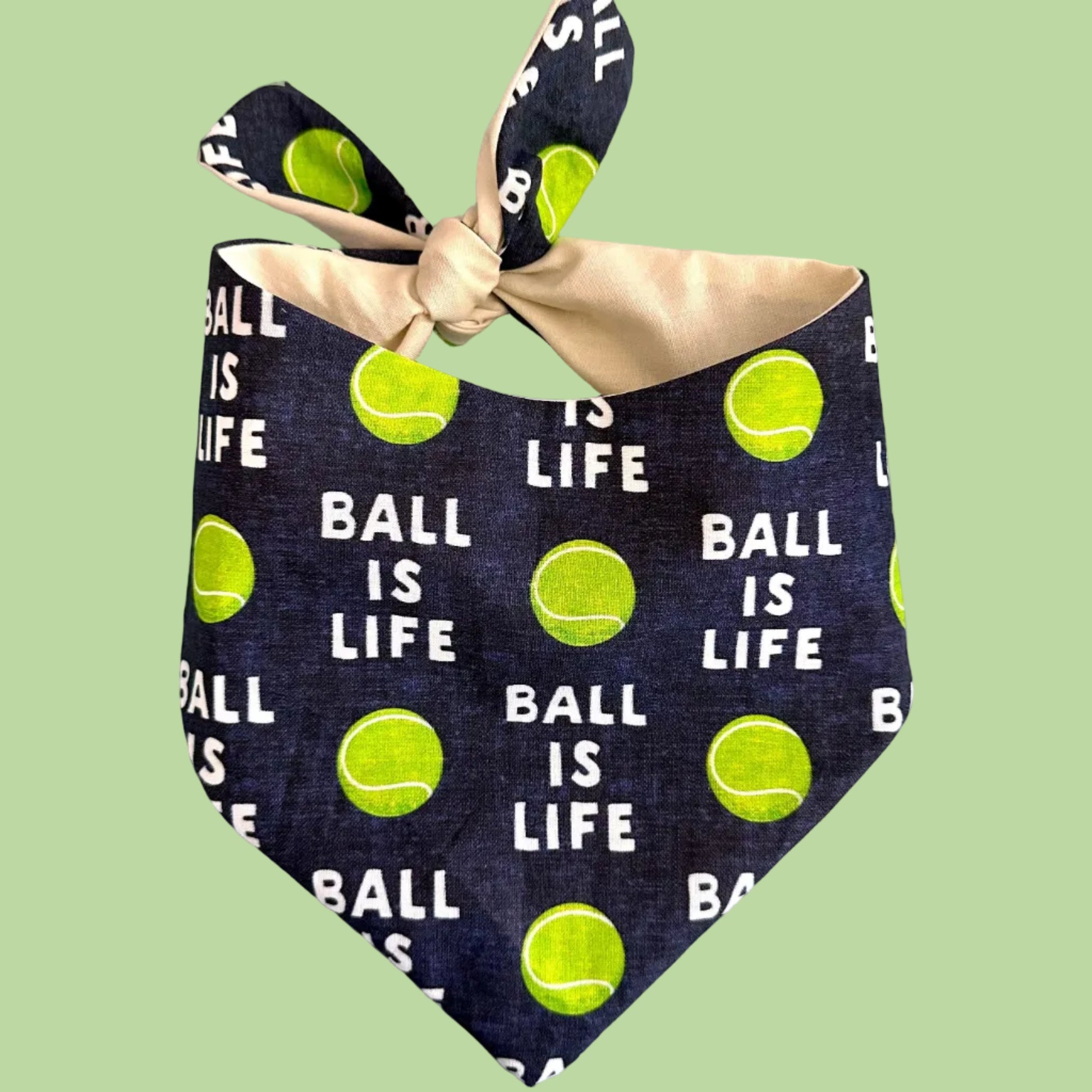 Navy blue bandana with tennis ball pattern and 'Ball is Life' text on a light green background