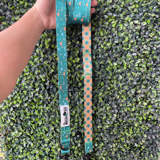 Teal dog leash with pattern held by a hand on a green artificial grass background
