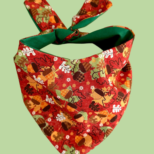 Colorful dog bandana with autumn-themed design on a beige background