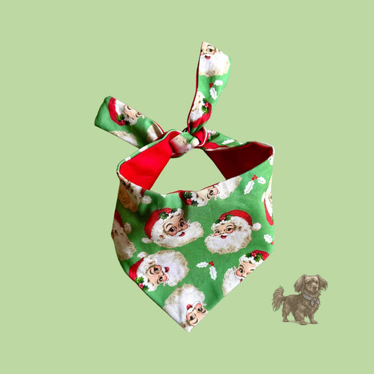 Christmas-themed dog bandana with Santa Claus pattern on a green background