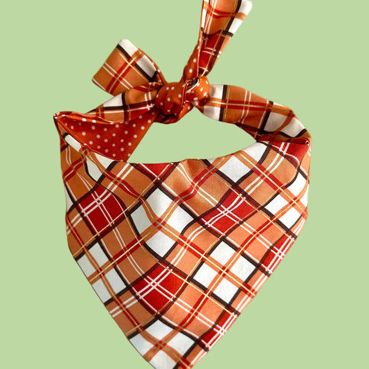 Plaid patterned dog bandana with a bow on a beige background