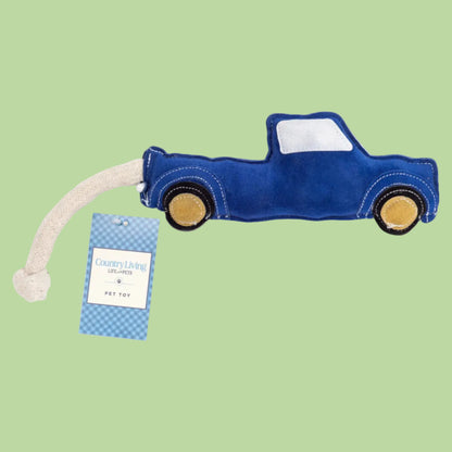 Blue truck-shaped dog toy with a rope and tag on a white background